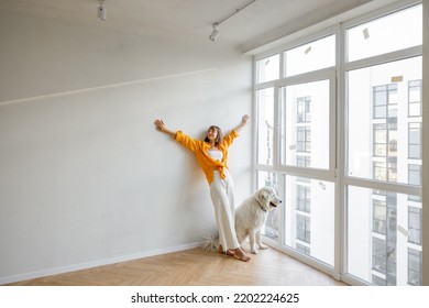 Young woman enjoy new apartment while stands with her dog near the window in bright room. Friendship with pet and house renovation concept - Powered by Shutterstock