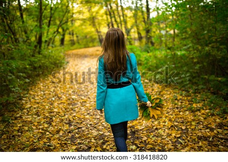 Young woman enjoying in autumn park playing with leaves