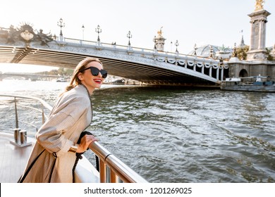 Young woman enjoying beautiful landscape view on the riverside from the tourist ship during the sunset in Paris