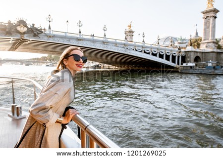 Young woman enjoying beautiful landscape view on the riverside from the tourist ship during the sunset in Paris