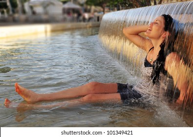 Young Woman Enjoying Cold Water Falls Fountain On A Heat Wave Day. Concept Photo Of Hot Weather, Heat Wave, Global Warming, Summer Season,climate Change,woman,freedom,lifestyle. Real People.Copy Space