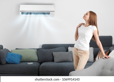 Young woman enjoying cool air flow from conditioner at home