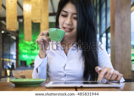 Young woman enjoying a cup hot coffee and using tablet pc at the coffee shop