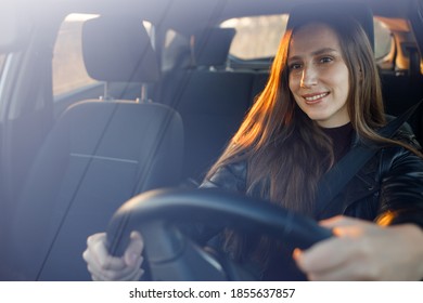 Young woman enjoying driving car at sunset. Travelling by automobile