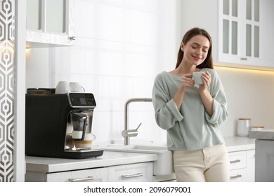 Joven disfrutando de café aromático fresco cerca de una máquina moderna en la cocina