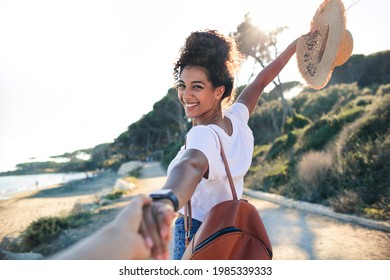 Young woman enjoying her vacation at the sea -Woman walking on a path by the beach, holding a friend's hand - Concept of freedom enjoyment
