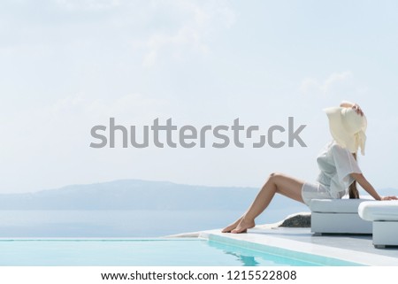 young woman enjoying a magnificent view of Santorini near the pool.