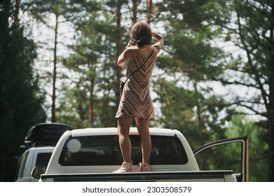 Young woman enjoying a moonlit night on top of his camper van. - Powered by Shutterstock