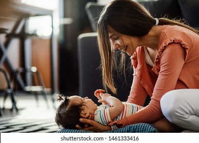Young woman enjoying in motherhood while spending time with her baby daughter at home.