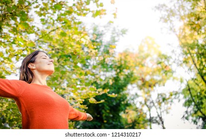 Young Woman Enjoying Nature With Her Arms Outstreched Towards The Sun. Smelling The Fresh Air.