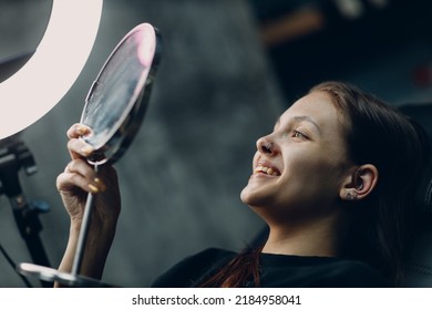 Young Woman Enjoying Piercing Nose Ring Watching Mirror With Smile