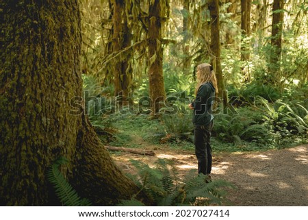 Young woman enjoying a quiet moment on a hike in the Hoh Rainforest in Olympic National Park.