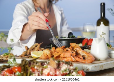 Young woman enjoying seafood platter during the sunset in the beach restaurant	