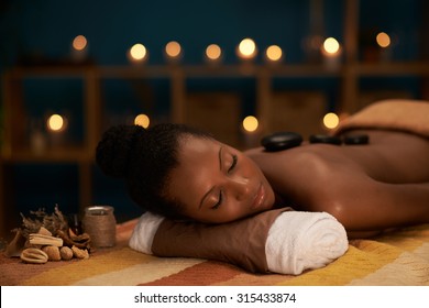 Young woman enjoying stone massage in luxury spa salon