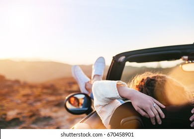Young woman enjoying the sunset from a convertible