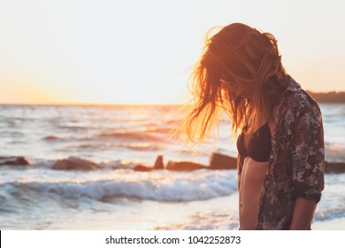 Young woman enjoying sunset and waves at the beach - Shutterstock ID 1042252873