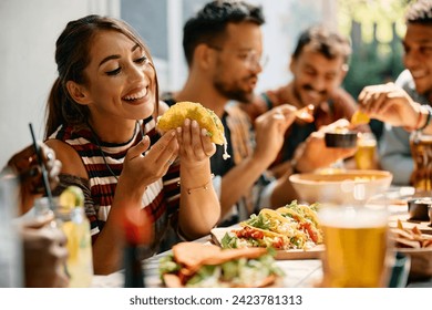 Young woman enjoying in a taste of tacos while having lunch with friends in restaurant.  - Powered by Shutterstock