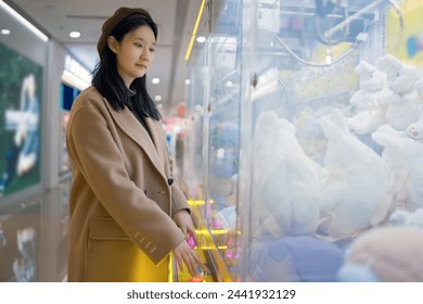 Young Woman Enjoying Time at Arcade Claw Machine