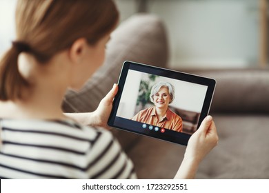 Young woman   enjoying video conversation via laptop with eldery mother while sitting on sofa during self isolation for coronavirus prevention  - Powered by Shutterstock