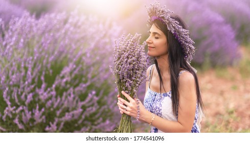 Young woman enjoying the view and the sunlight on her face on a rural flower field with lavender blossoms.