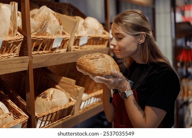 A young woman enjoys the aroma of fresh bread at a busy bakery, showcasing various artisanal products - Powered by Shutterstock