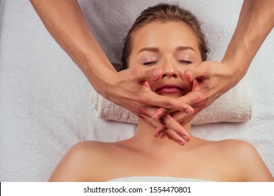 Young Woman Enjoys Ayurvedic Facial Massage In Luxury Resort Dark Lighting