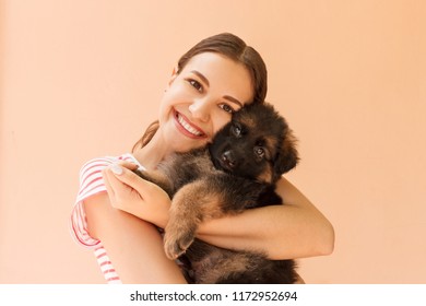 Young woman enjoys hugging a small cute puppy.