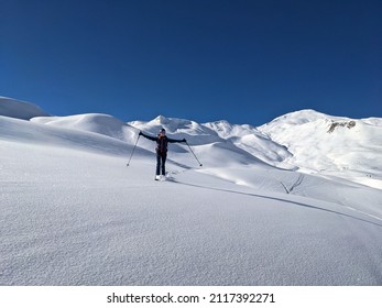 young woman enjoys the snow-covered mountain landscape with a deep snow descent in St. Antonien. Enjoy life. Skitouring