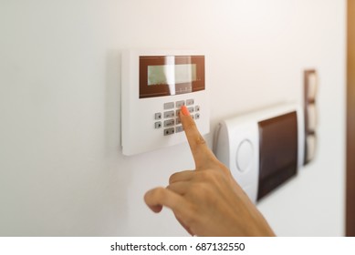 Young woman entering authorization code pin on home alarm keypad. Home security concept