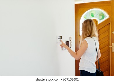 Young Woman Entering Authorization Code Pin On Home Alarm Keypad. Home Security Concept