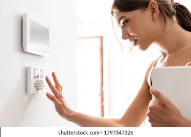 Young woman entering code on keypad of home security alarm