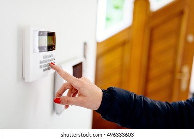 Young woman entering security code on home security alarm system keypad