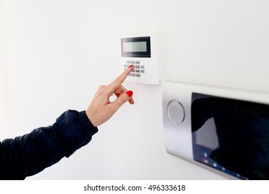 Young Woman Entering Security Code On Home Security Alarm System Keypad