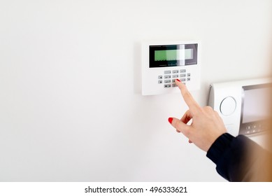 Young Woman Entering Security Code On Home Security Alarm System Keypad