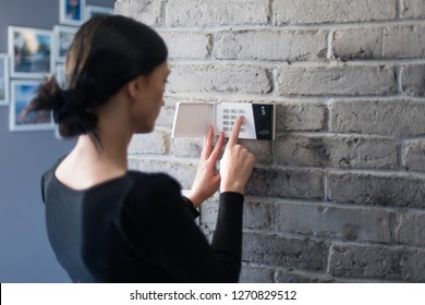 Young woman entering security pin on home alarm keypad. Home security system