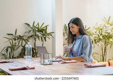 Young woman entrepreneur or creative freelancer working on laptop in cafe or at home - Shutterstock ID 2255697601