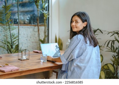 Young woman entrepreneur or creative freelancer working on laptop in cafe or at home - Shutterstock ID 2256816585