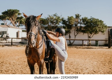 Young Woman In Equestrian Clothing Getting On A Horse