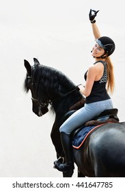 Young Woman In Equestrian Outfit Riding A Horse. Girl Shows Gesture 