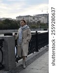 A young woman of European appearance is drinking coffee on the waterfront in the city