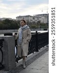 A young woman of European appearance is drinking coffee on the waterfront in the city