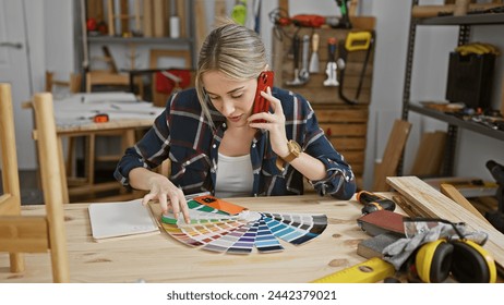 A young woman examines color swatches while talking on the phone in a well-organized carpentry workshop. - Powered by Shutterstock