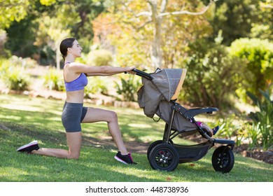 Young woman exercising with baby stroller in park