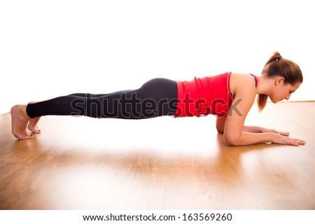 Young woman exercising - doing a plank in a studio