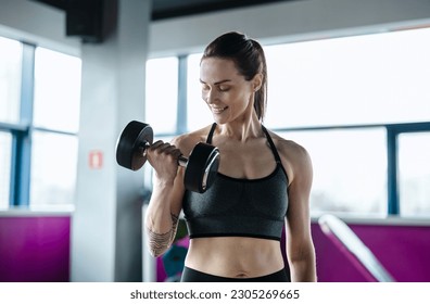 Young woman exercising with dumbbells in a health club
				