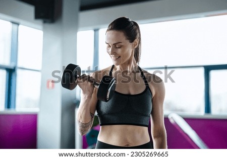 Young woman exercising with dumbbells in a health club
