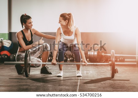 Young woman exercising at the gym with a female personal trainer.