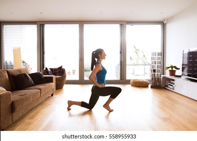 Young Woman Exercising At Home, Stretching Legs.