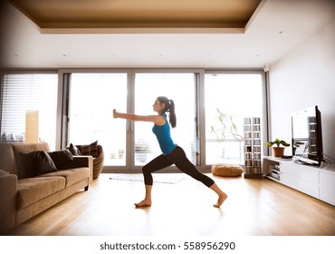 Young Woman Exercising At Home, Stretching Legs And Arms.