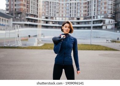 Young Woman Exercising With A Kettlebell Outside At Stadium